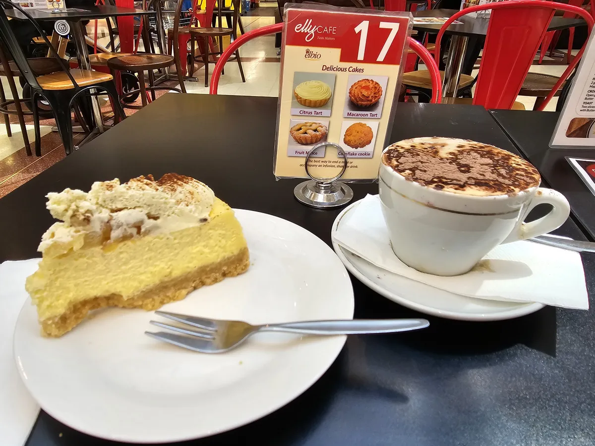 Slice of baked cheesecake with cream and a cappuccino